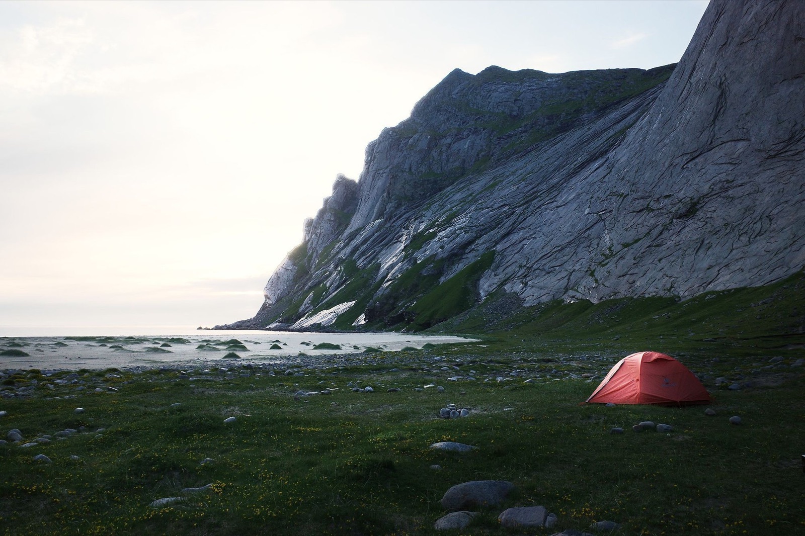 Red tent on a Lofoten beach with the mountain wall in the background