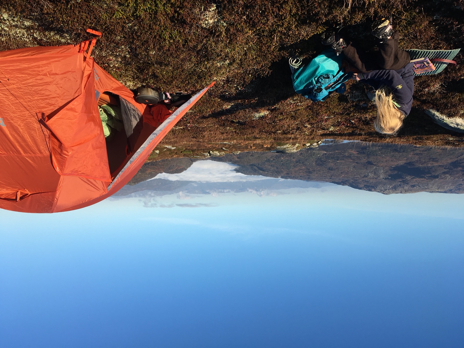 Orange tent on a mountain ridge above a layer of cloud