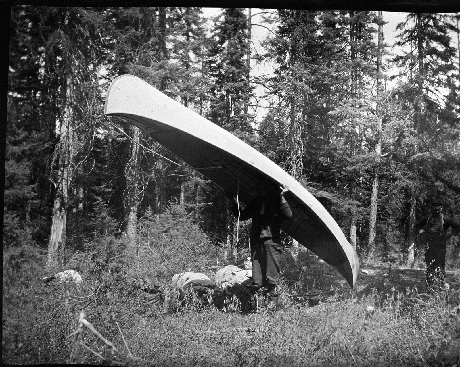 Familie i åpen kano på speilblank innsjø, med fjell i bakgrunnen