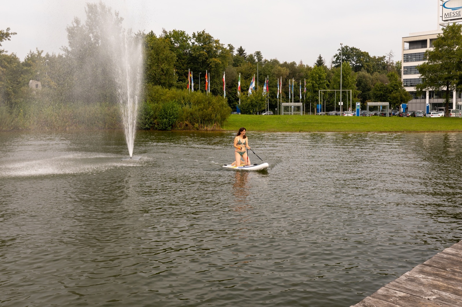 SUP-padler på speilblank innsjø, med skogkant i bakgrunnen