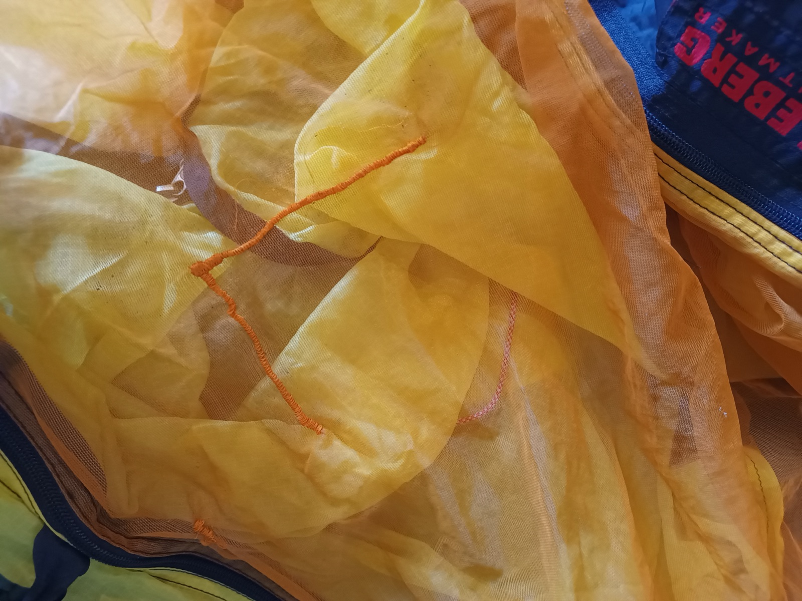 Sewing machine stitching over a tear in mosquito netting.