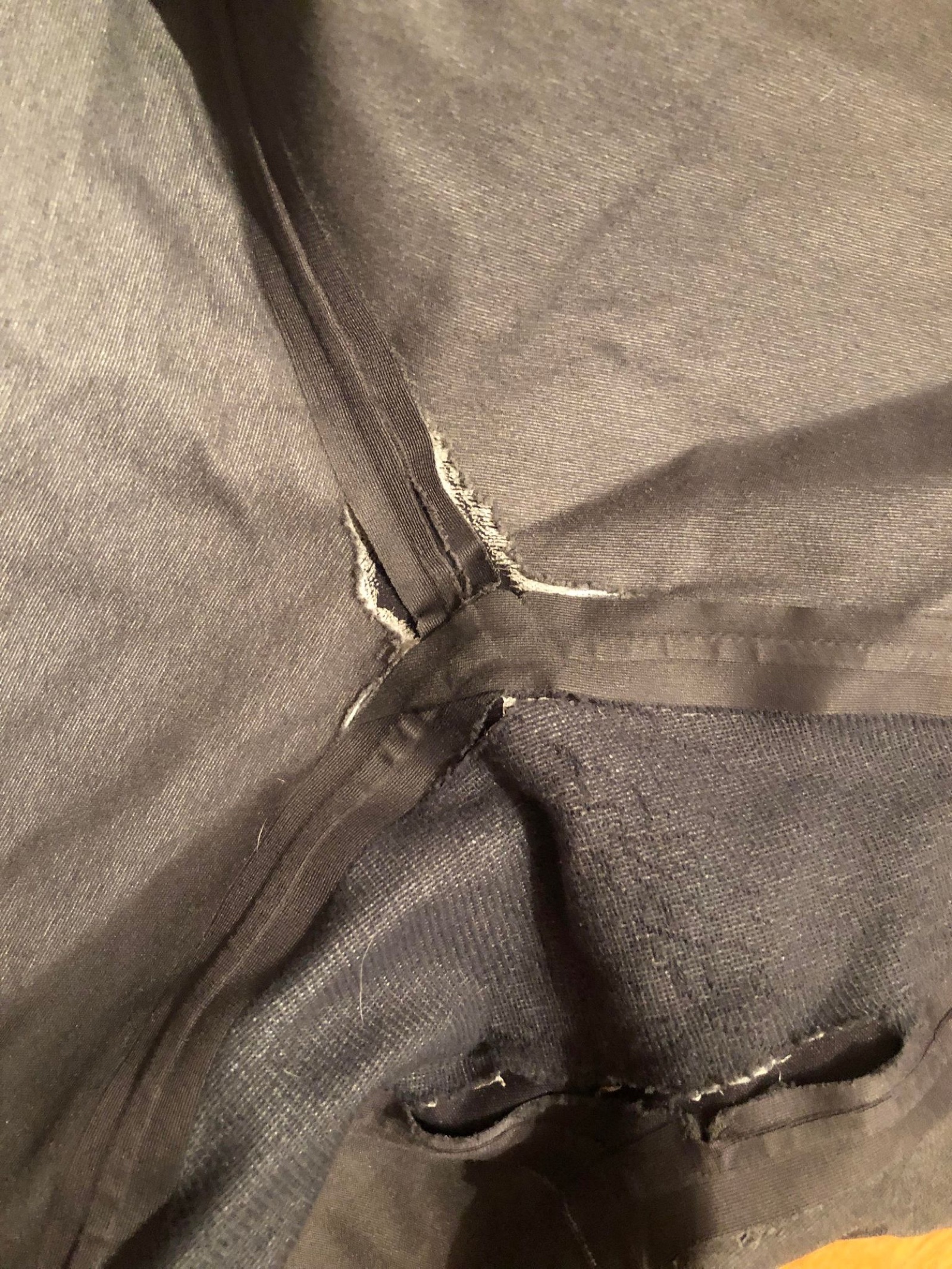 Trouser fabric under a sewing machine with a new patch and seam.