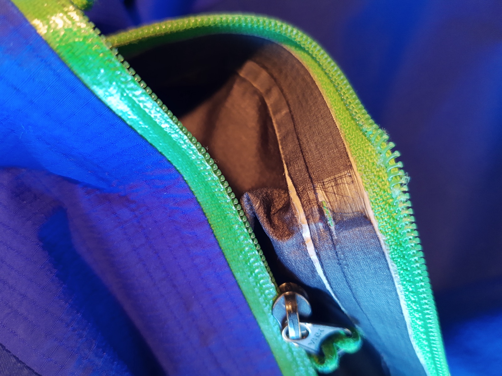 A sewing machine stitching down a loosened zip coil.
