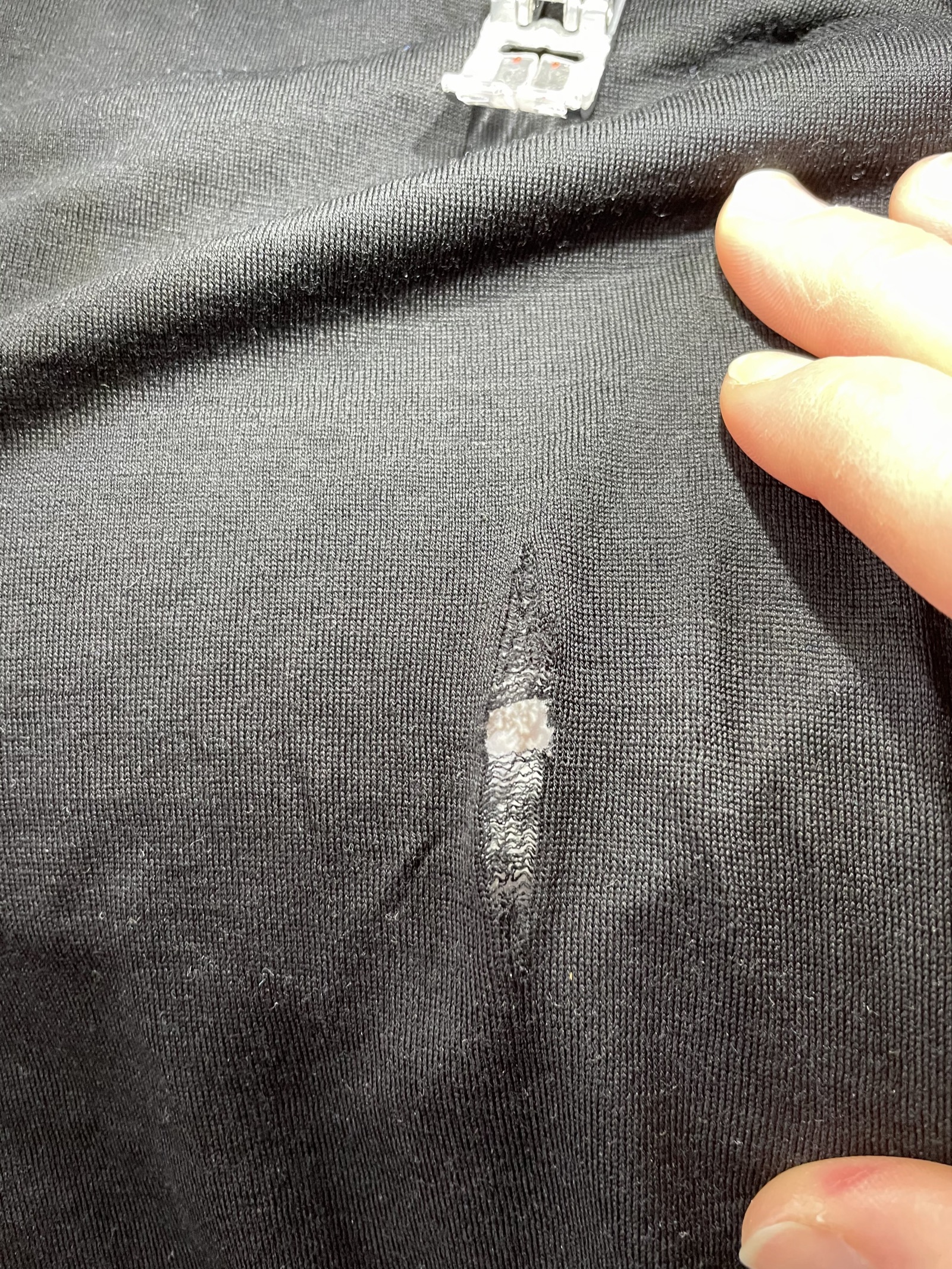 Sewing-machine work on woollen clothing with a reinforcing patch.