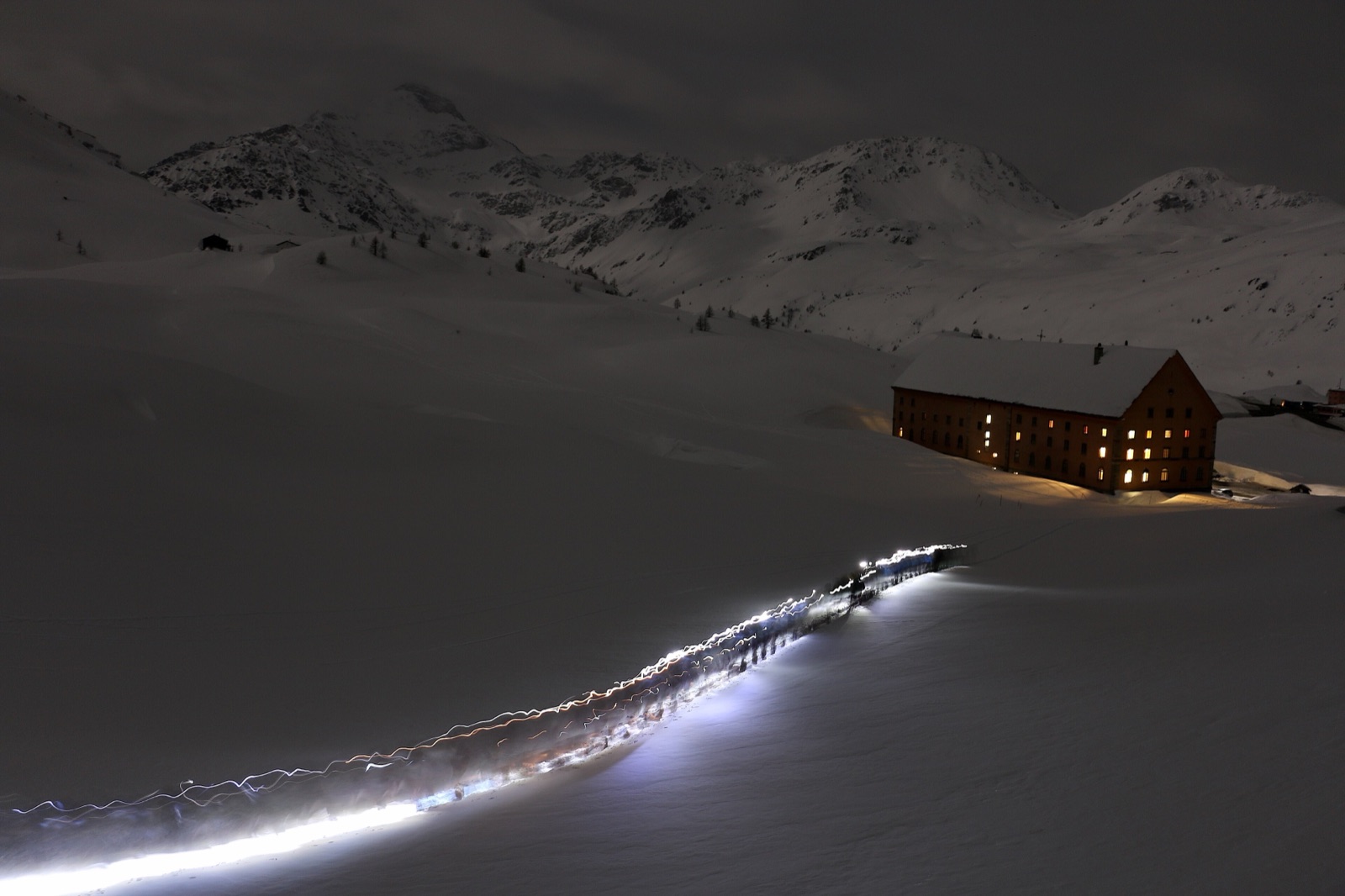 Night skiing with head torches in an alpine snow landscape.