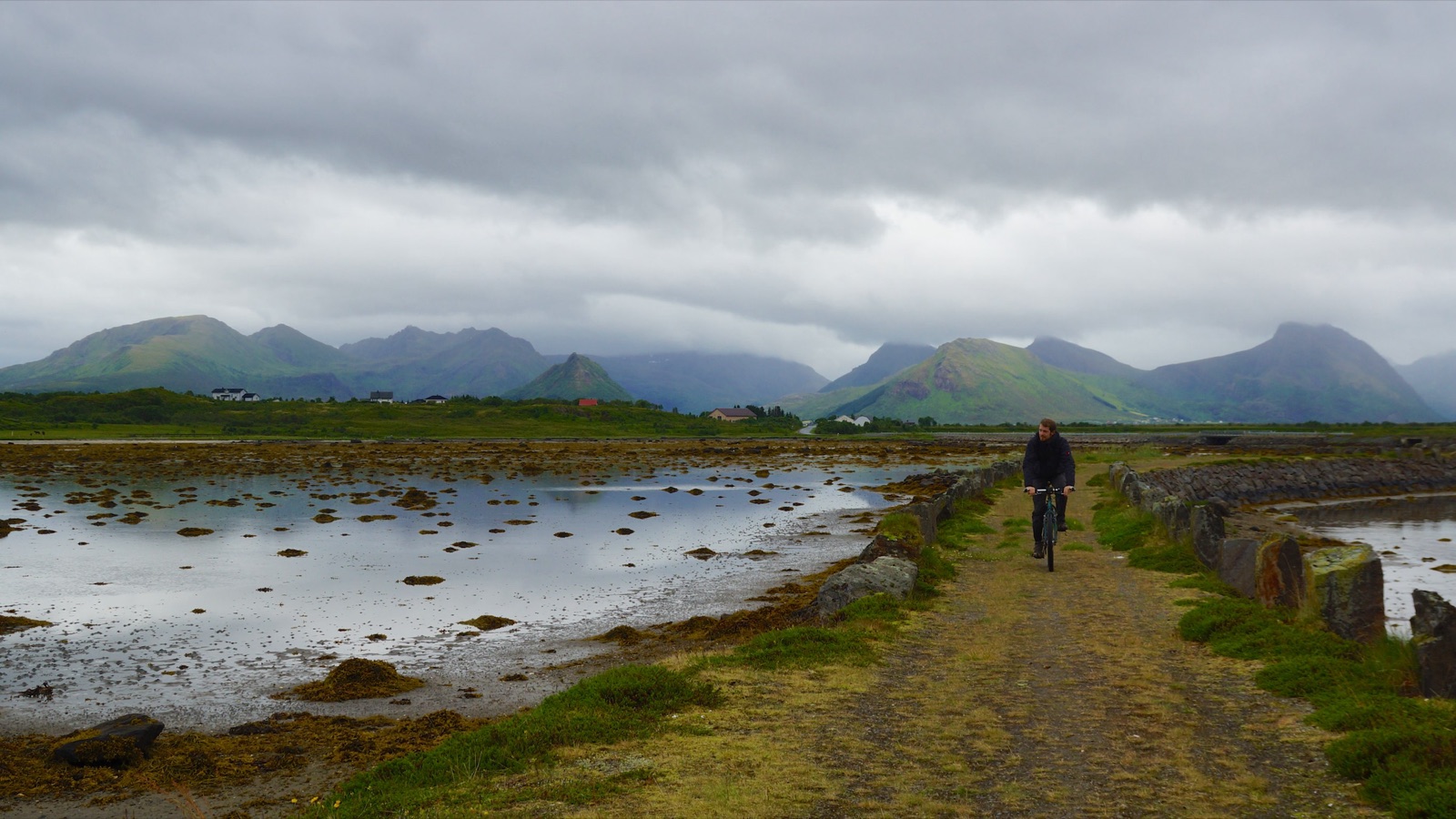 Cyclist on a gravel road through coastal landscape.