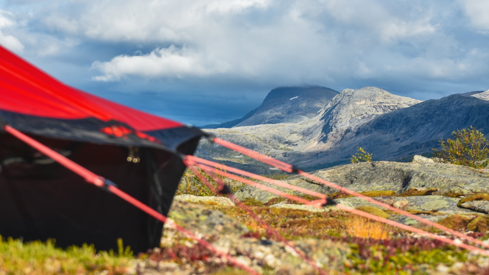Et rødt fjelltelt med snøskjørt i vinterterreng.