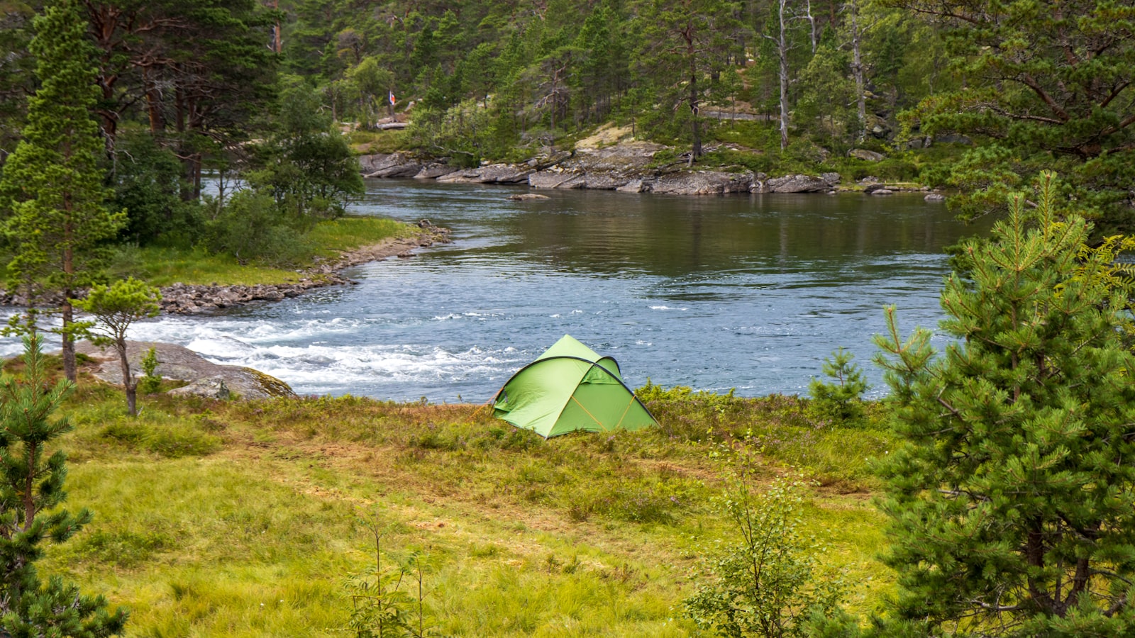 Et oransje kuppeltelt på fjellrygg.